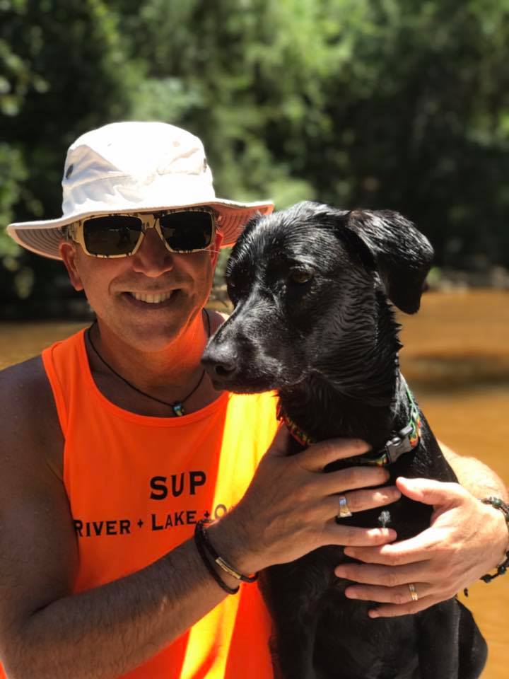 Descubre la Vida Bomber 31 Miembro del equipo de paddle board YOLO sentado con su perro con Bomber gafas de sol flotantes de camuflaje