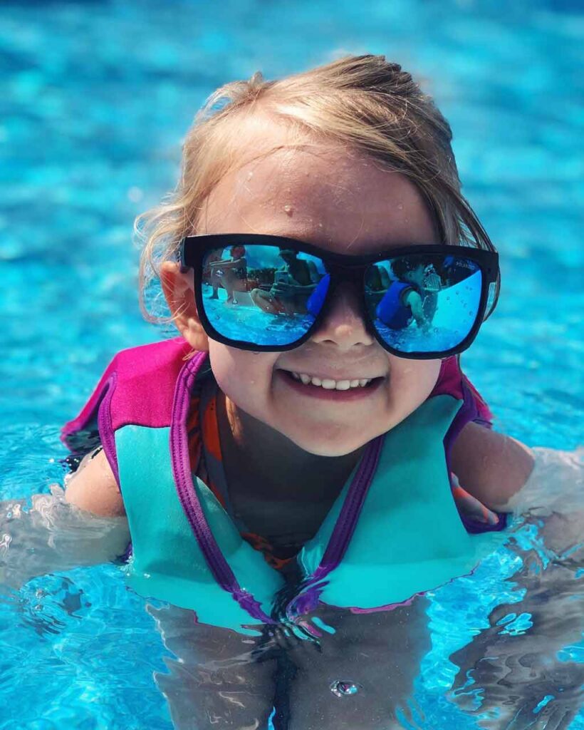 Descubre la Vida Bomber 18 Linda niña vistiendo Bomber flotante gafas y un chaleco de seguridad en una piscina