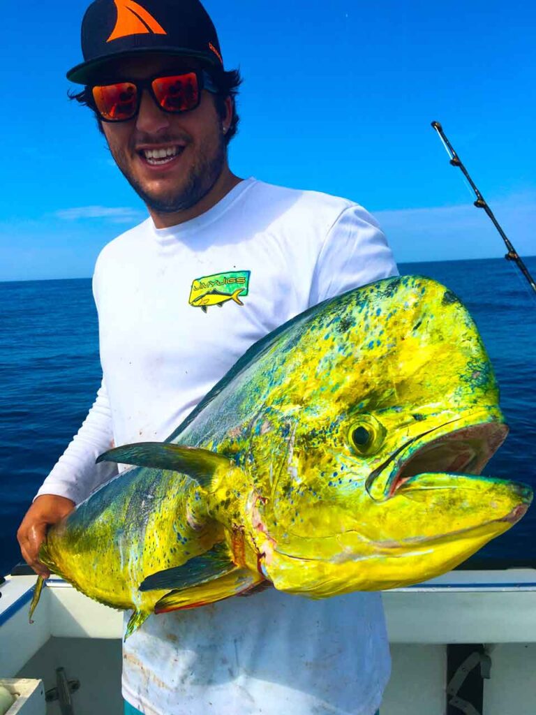 Descubre la Vida Bomber 16 Feliz pescador sosteniendo un gran tambor amarillo en un barco mientras usa gafas de sol flotantes polarizadas Bomber