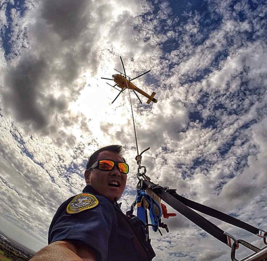Descubre la Vida Bomber 19 Trabajador de rescate escalando cuerda desde helicóptero con gafas de sol Bomber Safety